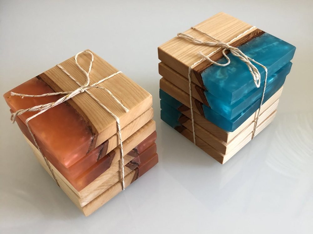 Stacks of wood and resin coasters tied with twine in ocean blue and sunset orange