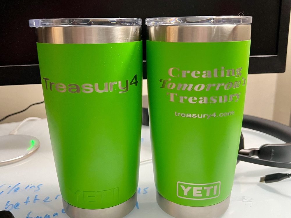 Two green insulated tumblers engraved with a client logo and tagline, shown close up