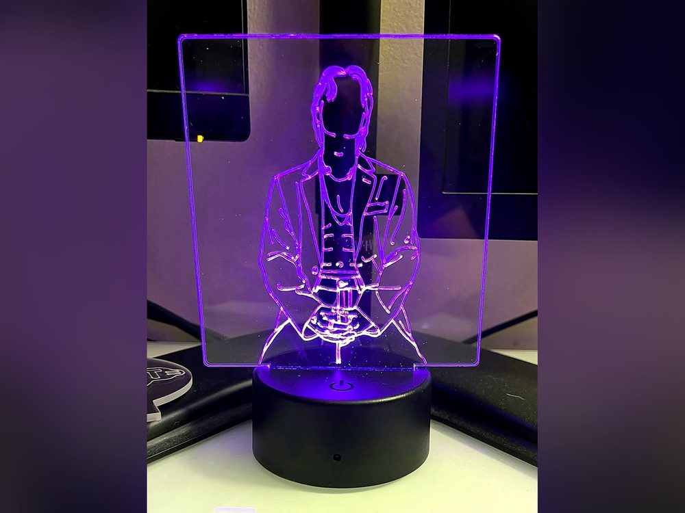 An engraved acrylic panel lit purple on a color-changing LED base with its remote