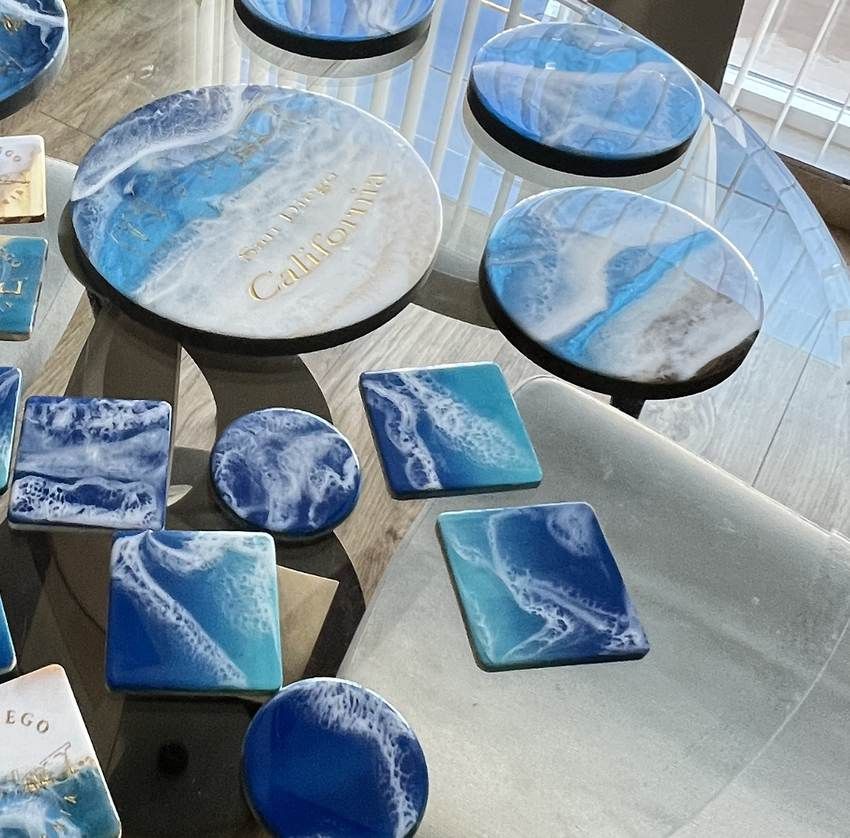 A hand-poured ocean resin piece with an engraved San Diego coastline beneath the foam line